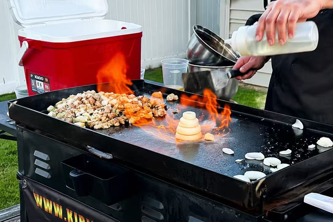 Hibachi chef pouring sauce with vibrant flames on the griddle